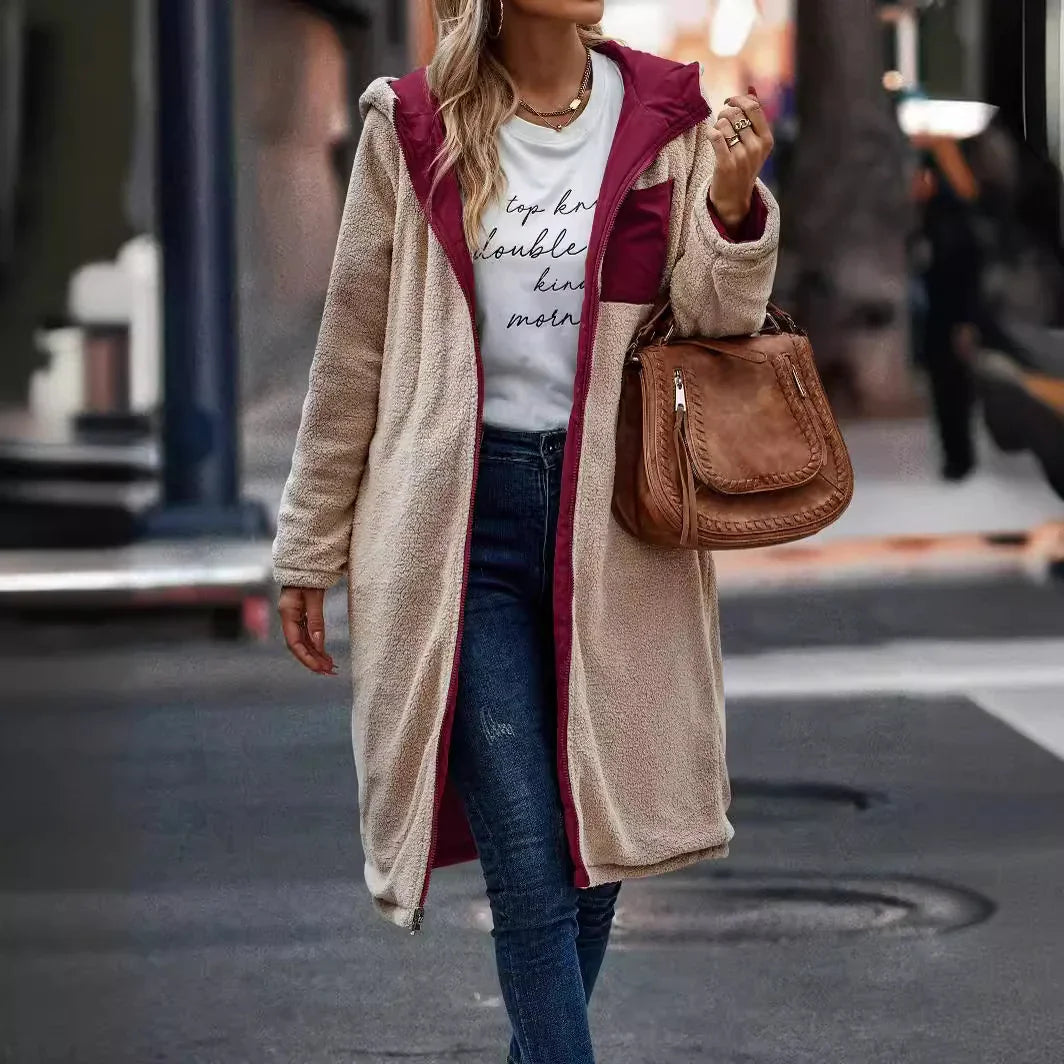 Woman wearing beige and burgundy sherpa fleece coat, white graphic tee, blue jeans, and carrying brown leather handbag