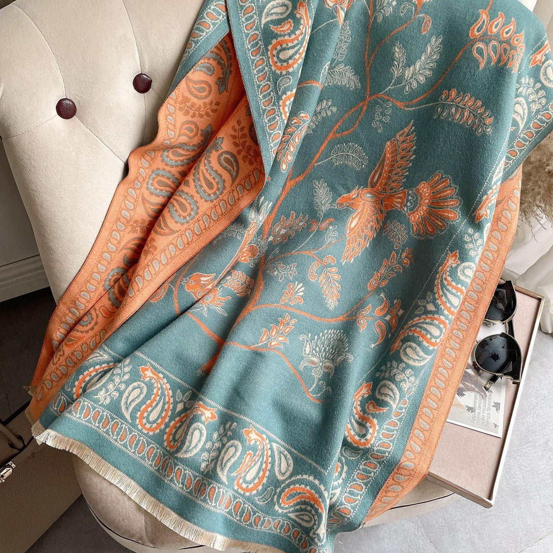 Decorative teal and orange paisley and bird pattern woolen throw blanket on beige tufted chair
