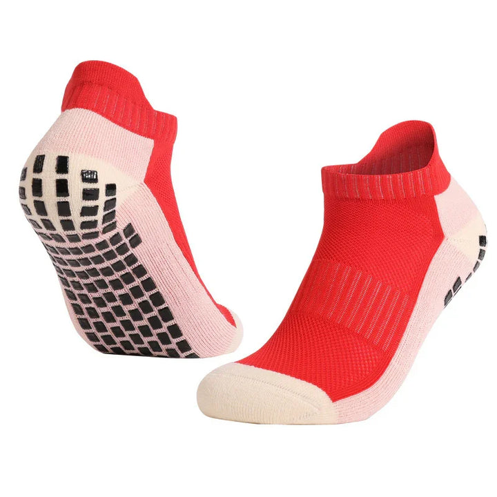 Pair of red and beige low-cut grip socks with black rubber sole dots for non-slip support