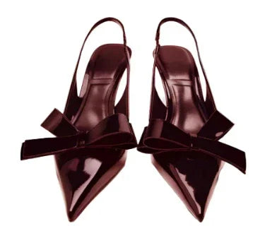 Pair of glossy dark burgundy pointed toe slingback heels with large decorative bows