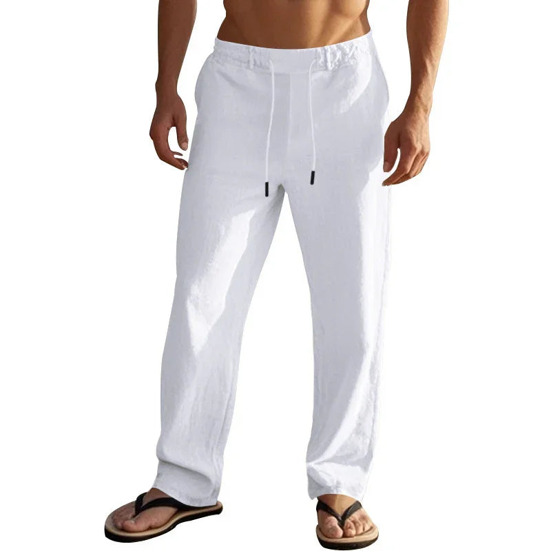 Man wearing white casual linen pants with drawstring and black flip-flops on white background