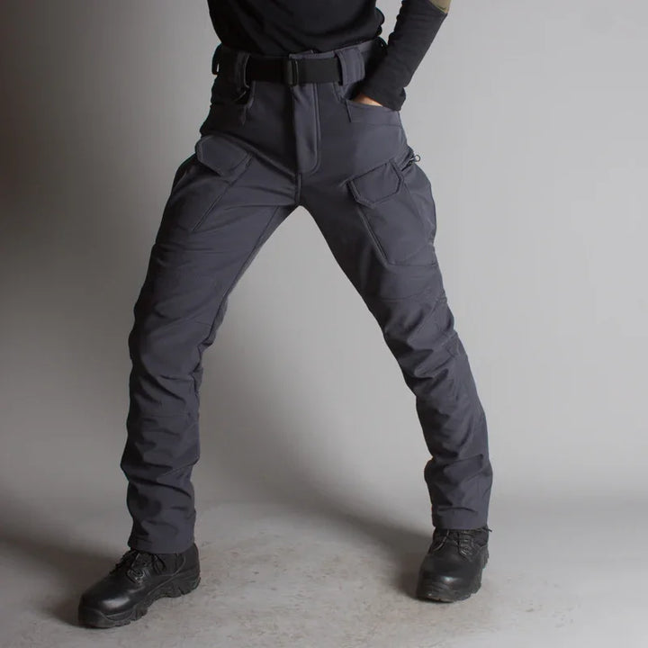 Person wearing dark gray tactical cargo pants with multiple pockets and black boots