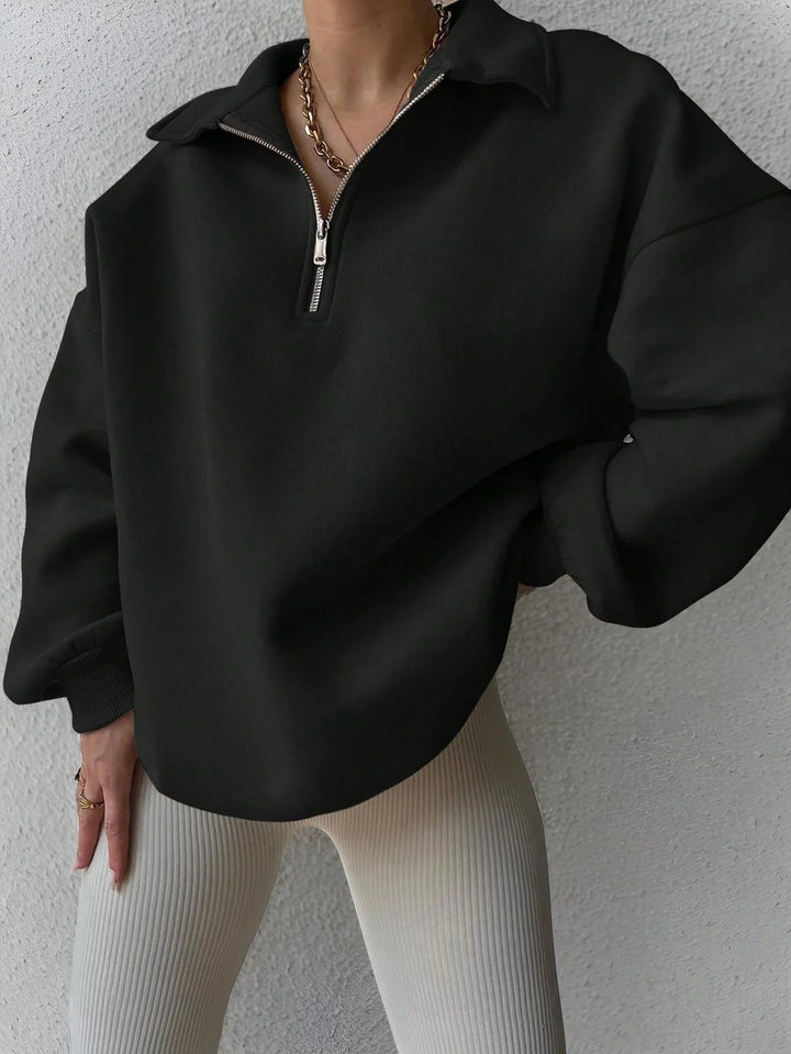 Woman wearing black half-zip pullover with beige ribbed leggings and gold chain necklace