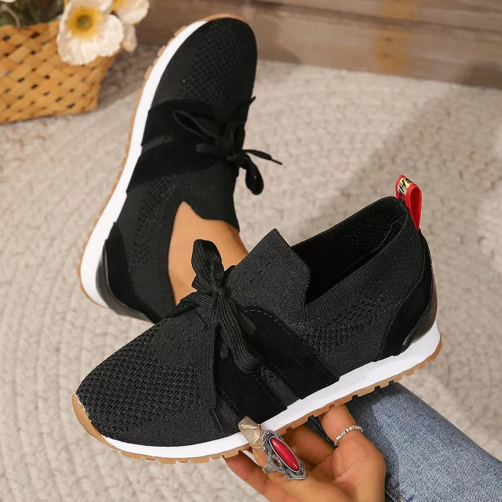 Black knit sneakers with white soles and gum outsole worn by person with rings on hand