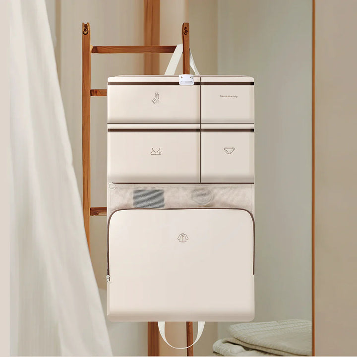 Beige travel packing organizer with compartments for socks, underwear, and shirts hanging on wooden ladder