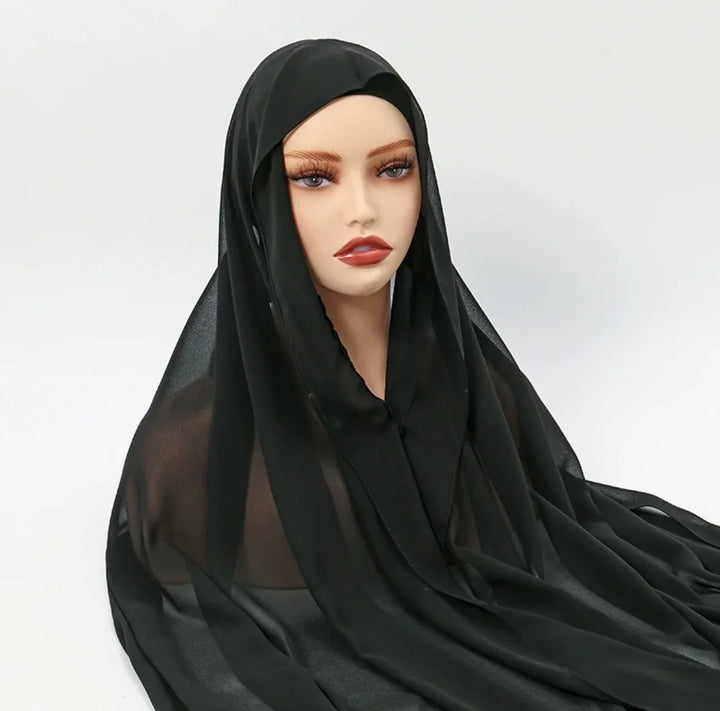 Mannequin wearing sheer black hijab scarf on white background, modest fashion