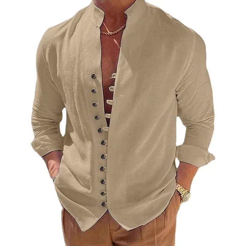 Man wearing beige mandarin collar long-sleeve shirt with buttons and brown pants, accessorized with gold watch and chain