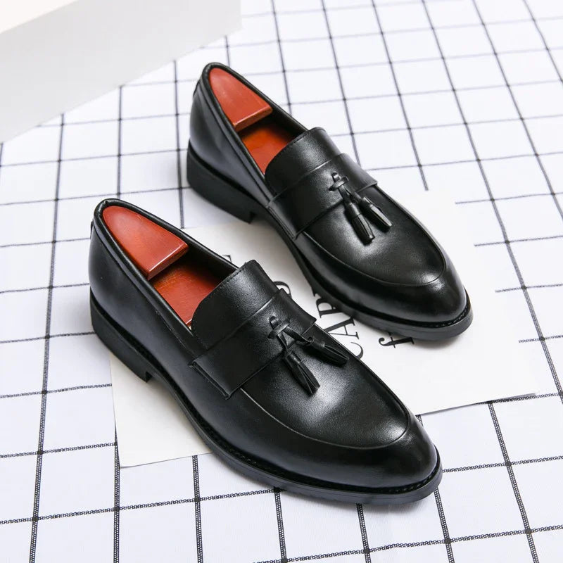 Black leather tassel loafers for men on a white grid background
