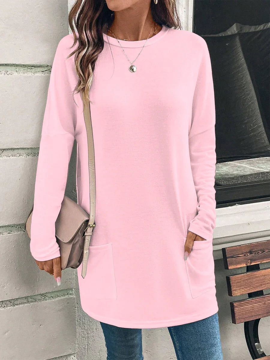 Woman wearing light pink long sleeve tunic sweater with front pockets and crossbody bag