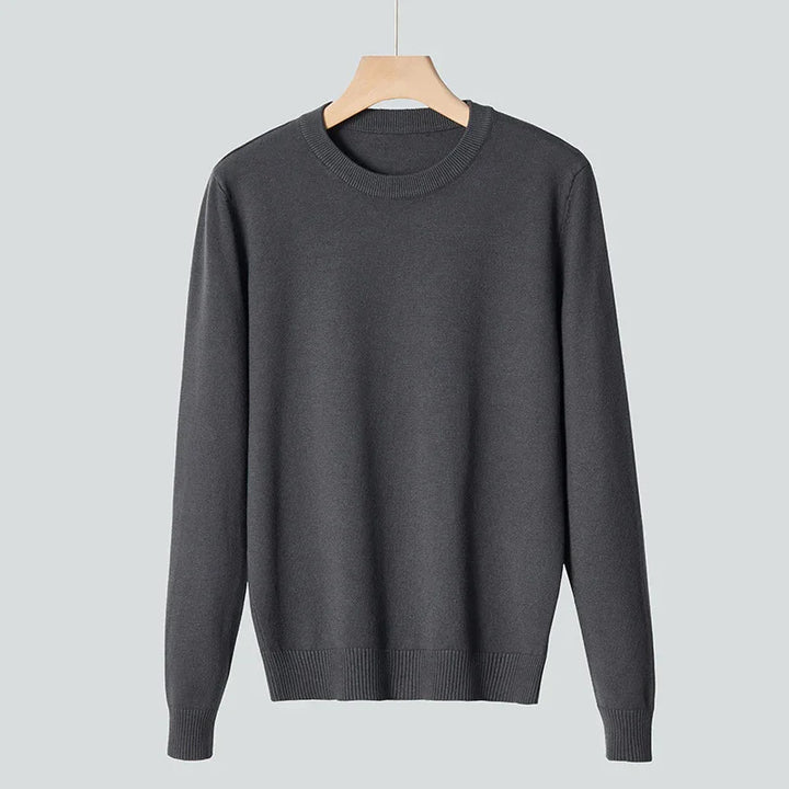 Dark gray crewneck sweater hanging on wooden hanger against light gray background