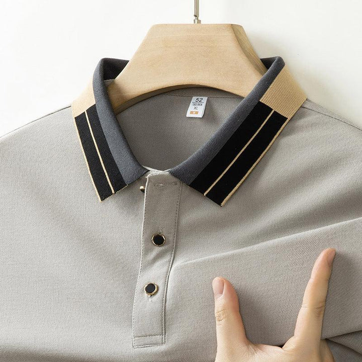 Close-up of a gray polo shirt with a beige and black striped collar on a wooden hanger, showing buttons and fabric texture