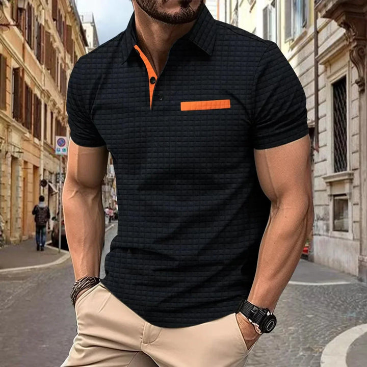 Man wearing black textured polo shirt with orange accents and beige pants on city street
