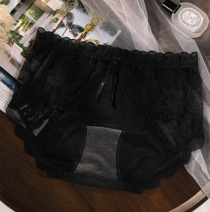 black lace and mesh women's underwear with scalloped edges and small bow detail on wooden surface