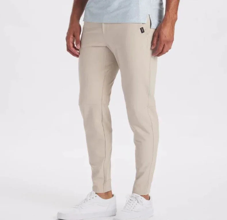 Men's beige slim fit jogger pants paired with white sneakers on white background