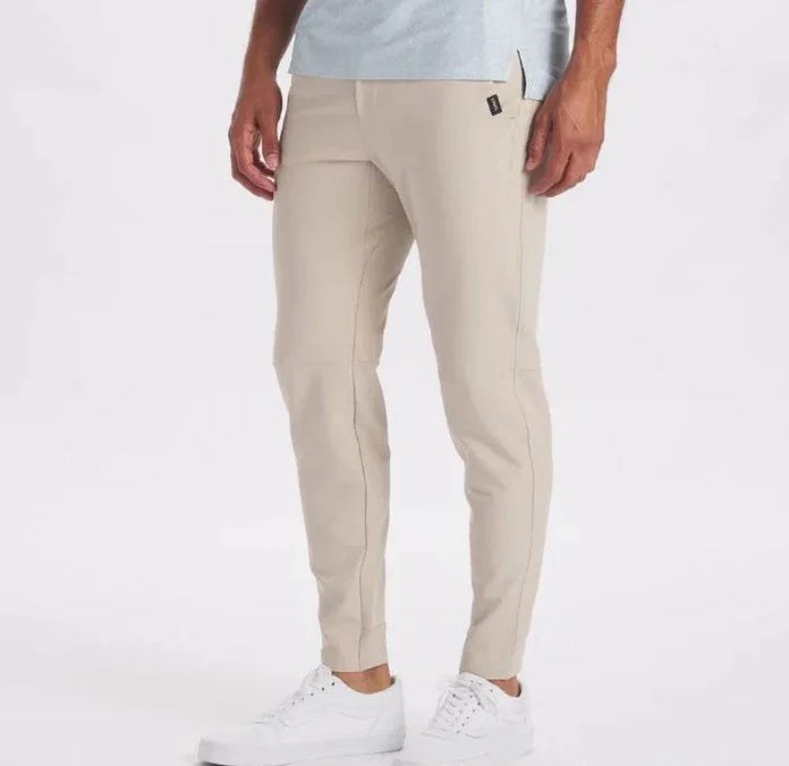 Men's beige slim fit jogger pants paired with white sneakers on white background