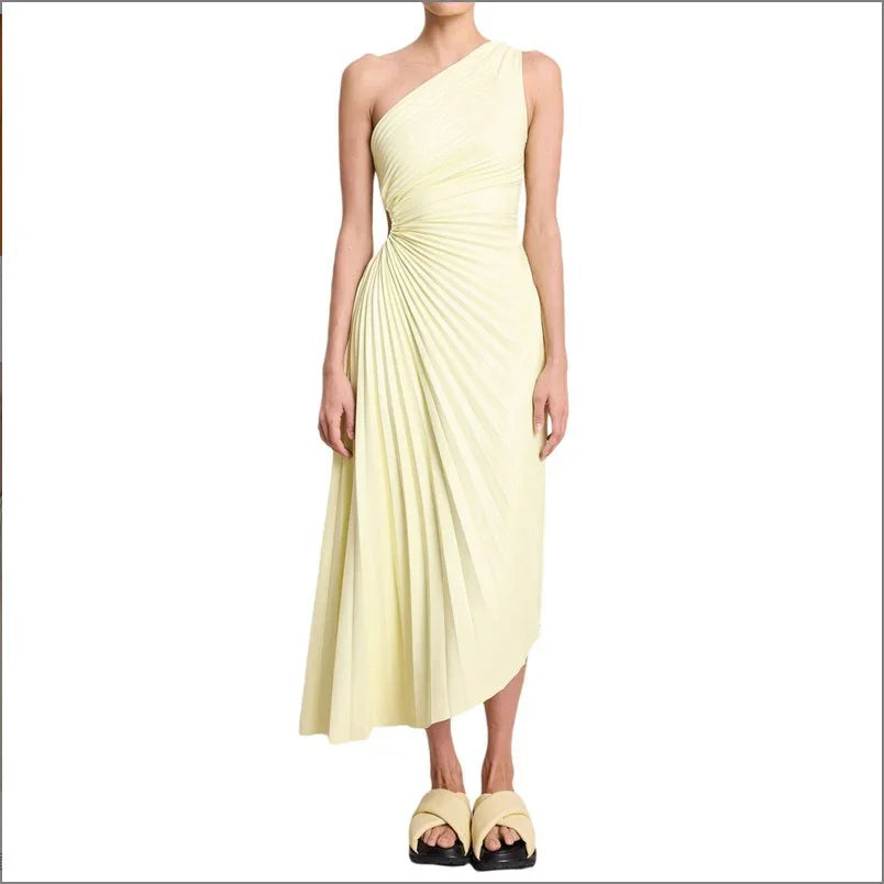 Woman wearing asymmetrical pale yellow pleated midi dress with one shoulder and platform sandals