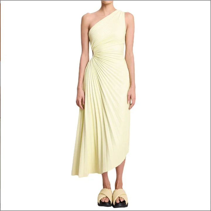 Woman wearing asymmetrical pale yellow pleated midi dress with one shoulder and platform sandals