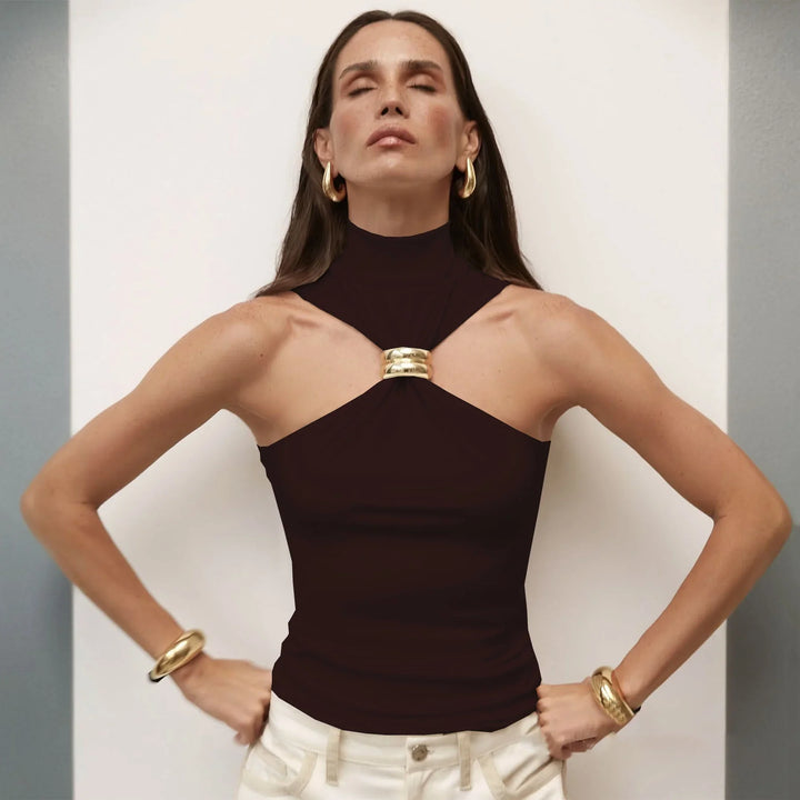 Woman in black sleeveless top with gold ring detail, gold hoop earrings, and bracelets, posing with eyes closed