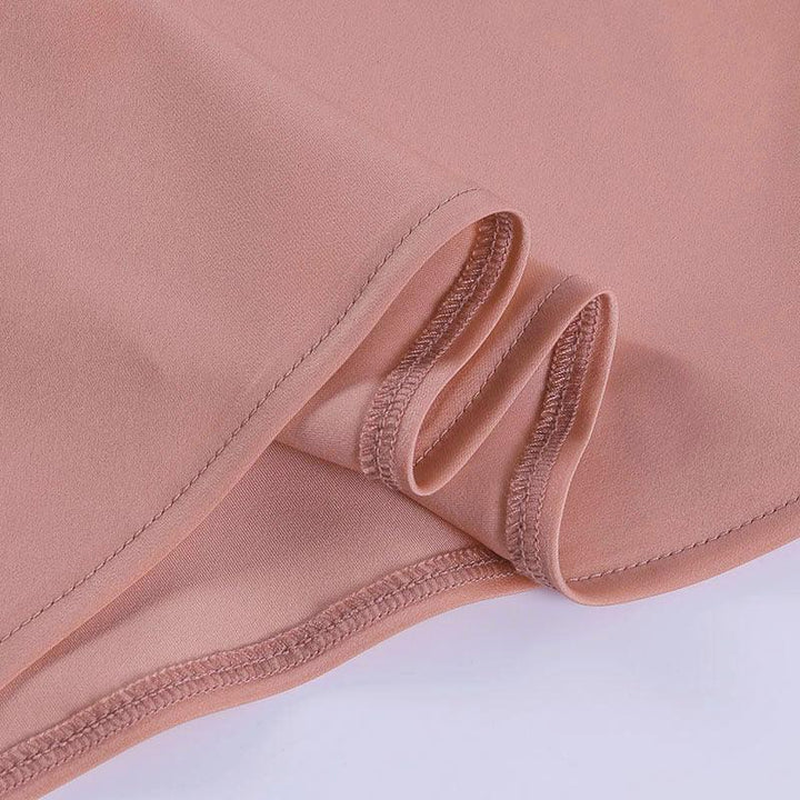 Close-up of smooth pink fabric with clean stitching and hem detail on light background