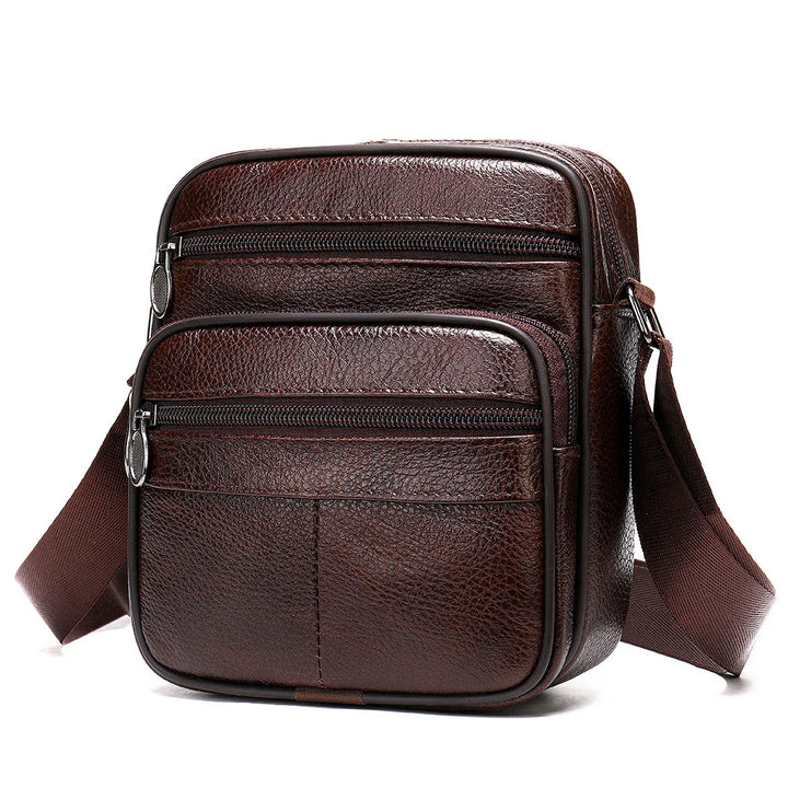 Dark brown leather crossbody sling bag with two zippered compartments and adjustable strap