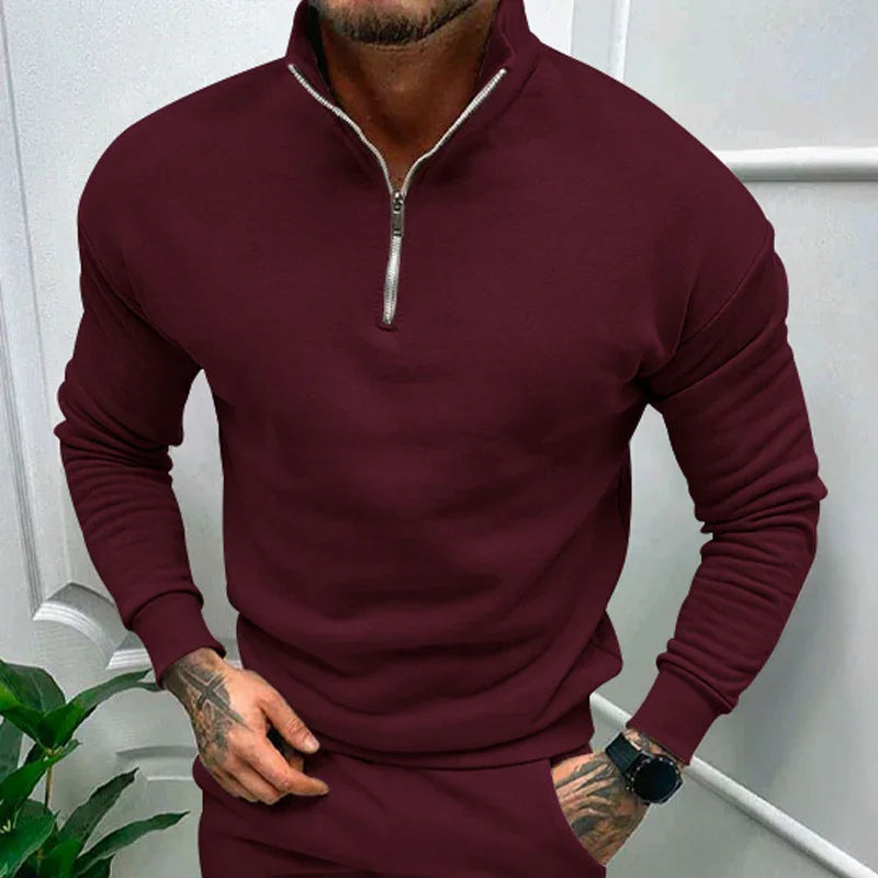 Man wearing burgundy quarter-zip pullover sweatshirt with long sleeves and matching pants indoors