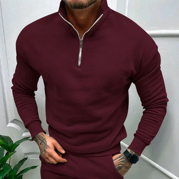 Man wearing burgundy quarter-zip pullover sweatshirt with long sleeves and matching pants indoors