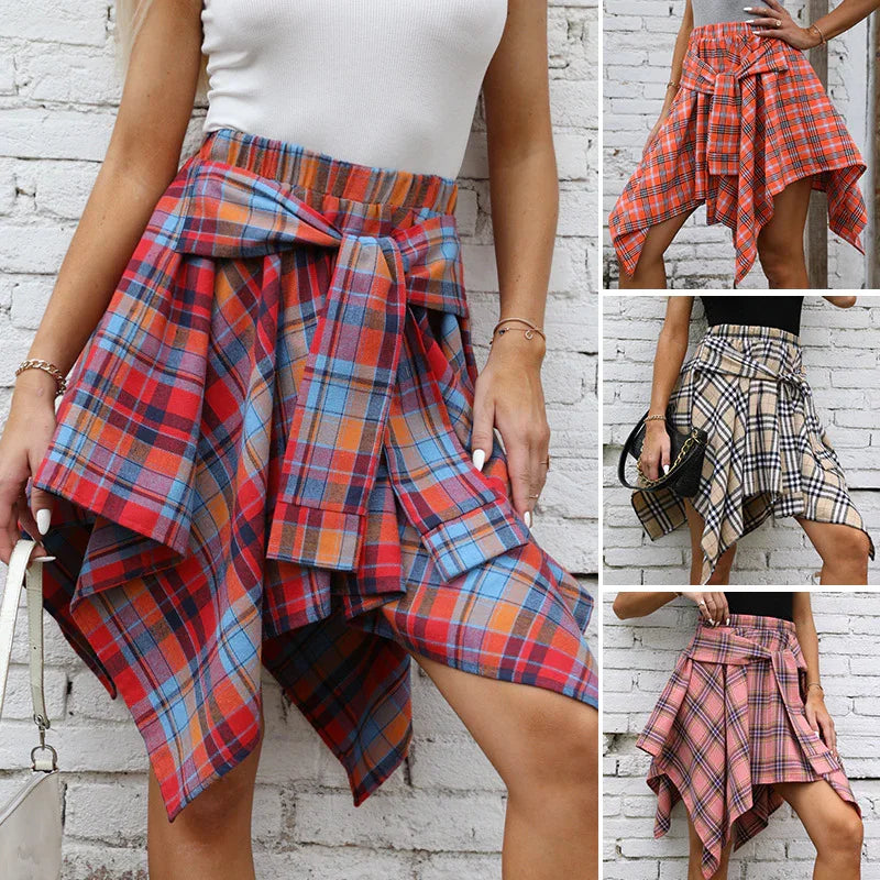Women wearing asymmetrical handkerchief plaid skirts in red, orange, beige, and pink, styled with tops and accessories against a white brick wall