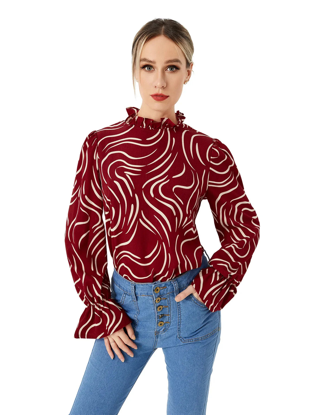 Woman wearing a red long-sleeve blouse with white abstract waves and ruffled collar, paired with high-waisted blue jeans