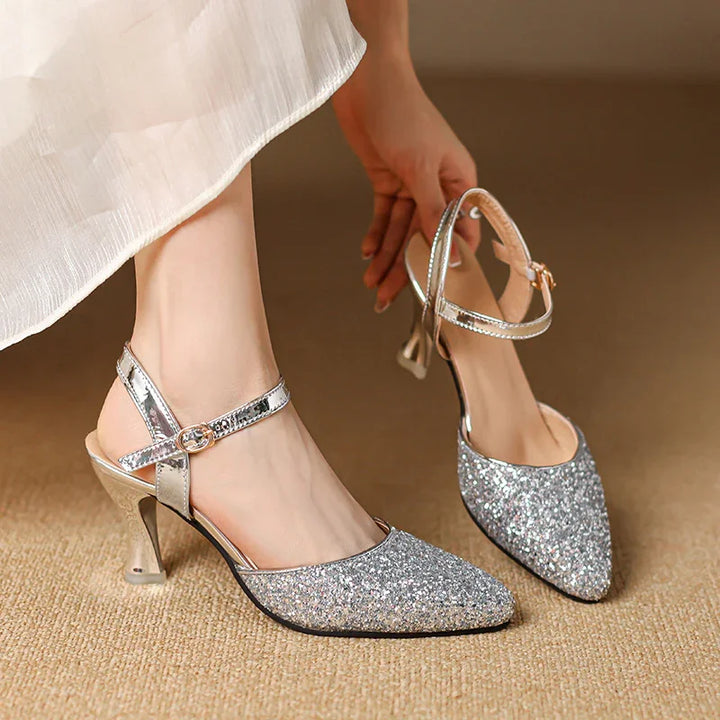 Woman wearing silver glitter pointed toe high heel slingback shoes with ankle strap