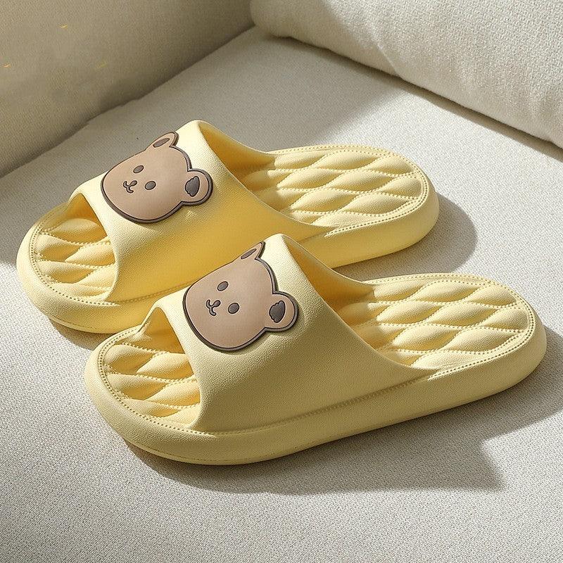 Yellow indoor slippers with quilted soles and cute brown bear faces on straps on beige surface