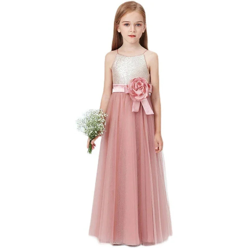 Young girl wearing a pink tulle flower girl dress with a sequined bodice and large floral belt holding a bouquet