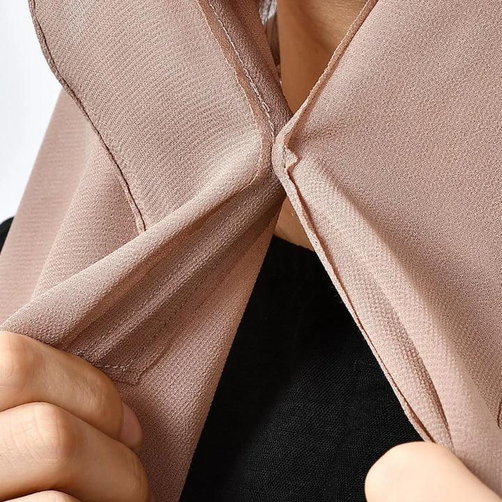 Close-up of a person holding and adjusting the collar of a pink textured fabric garment over a black shirt