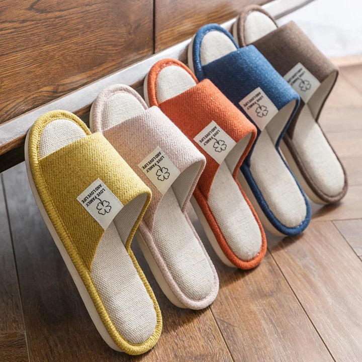 Colorful indoor fabric slippers lined up on wooden floor, featuring soft soles and a cotton label