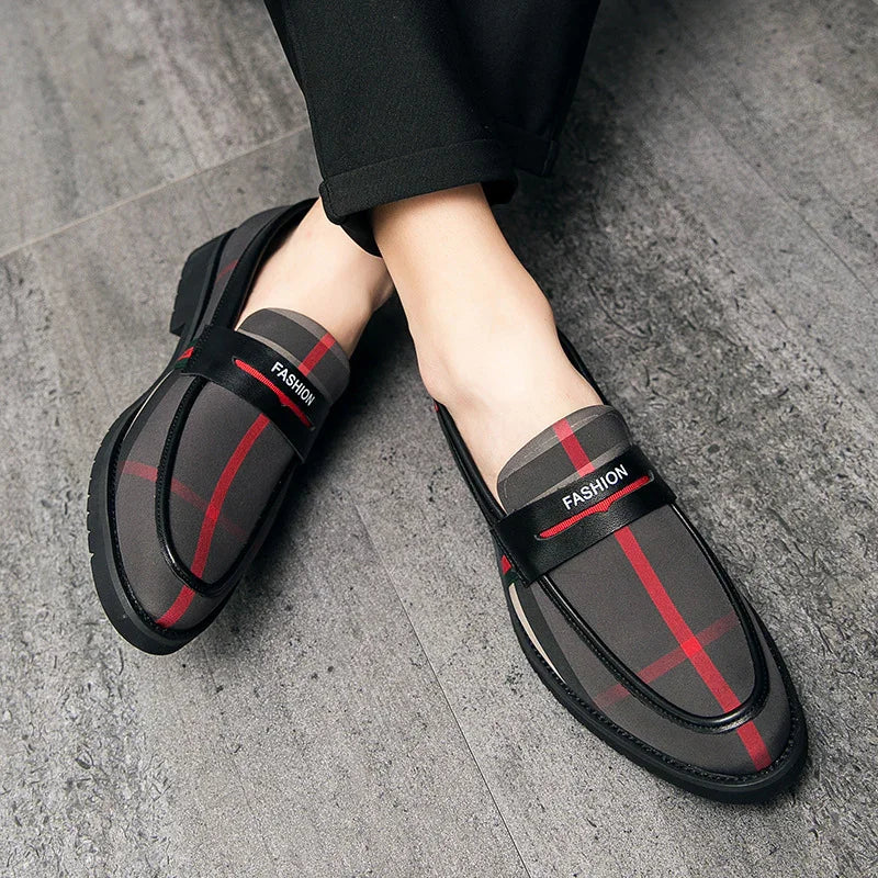 Stylish men's loafers with red and black plaid pattern and fashion strap on gray floor