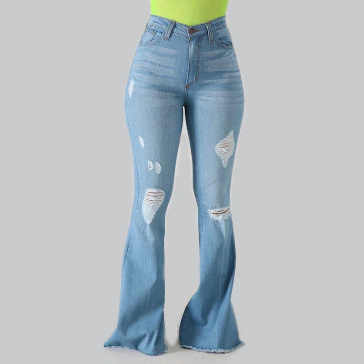 High-waisted light blue distressed flared jeans with ripped details and frayed hems