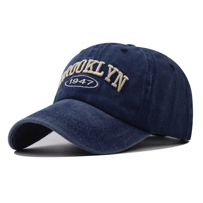 Navy blue baseball cap with beige embroidered text 'BROOKLYN 1947' on front