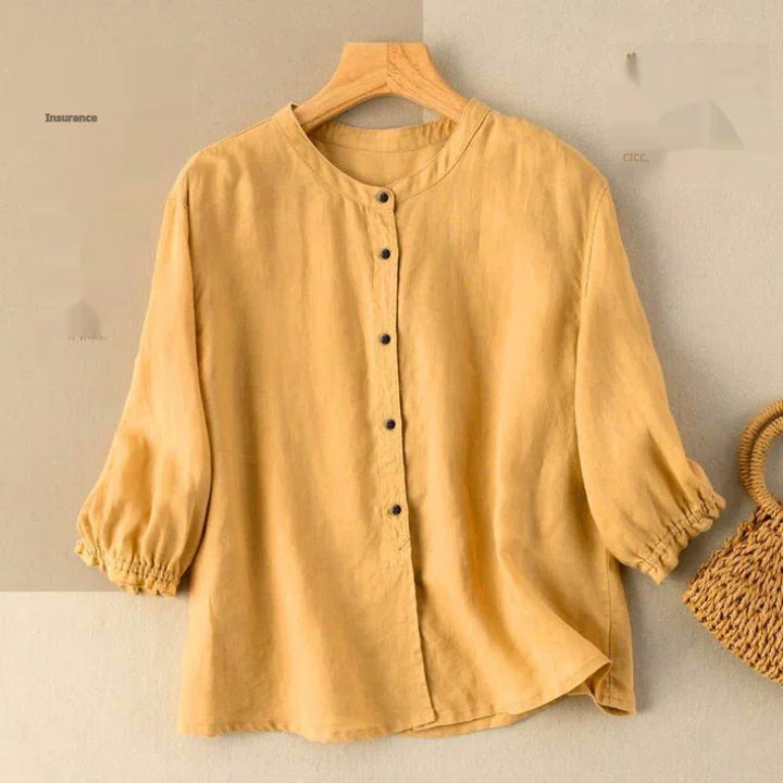 Mustard yellow lightweight linen blouse with round neck and button front on wooden hanger