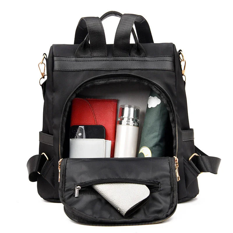 black backpack with open front pocket showing red wallet, phone, silver bottle, and umbrella inside