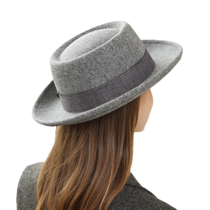 Rear view of person wearing a gray felt fedora hat with dark gray band and brown hair