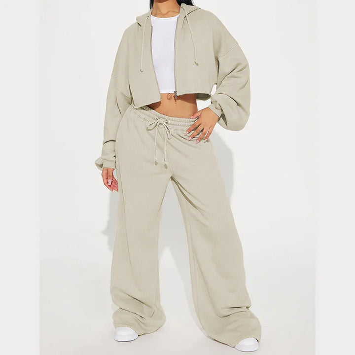 Woman wearing beige cropped hoodie and wide-leg sweatpants with drawstring, styled with white crop top and sneakers