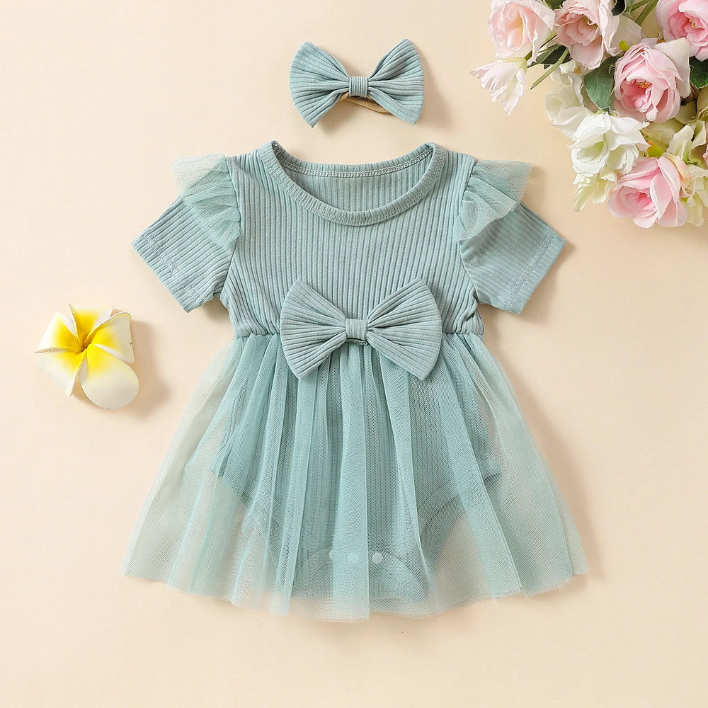 Mint green baby girl dress with tulle skirt and matching bow headband on beige background