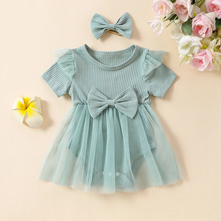 Mint green baby girl dress with tulle skirt and matching bow headband on beige background