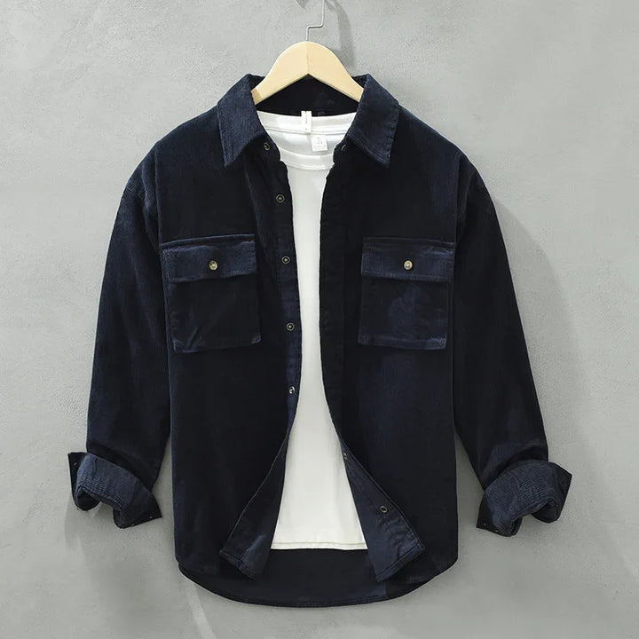 Black corduroy shirt jacket with buttoned chest pockets over a white t-shirt on hanger