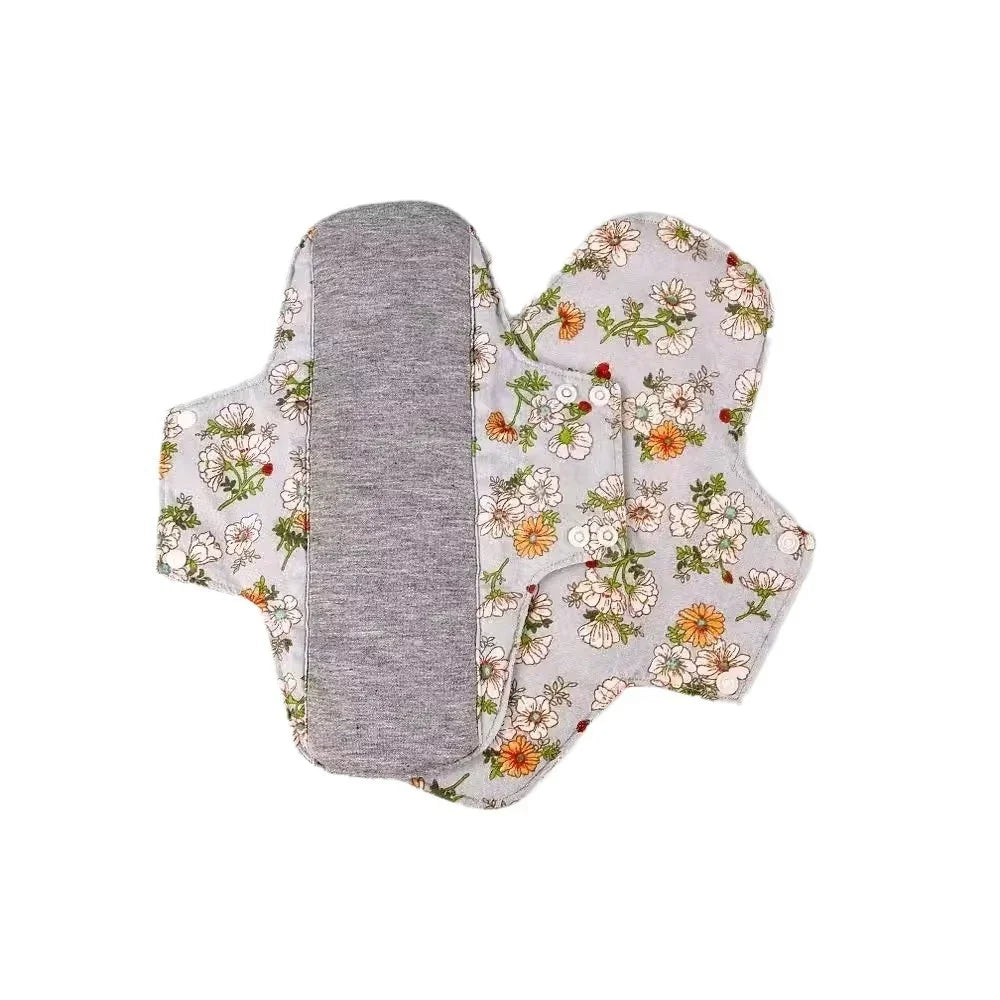 Reusable cloth menstrual pads with floral print and gray absorbent layer on white background