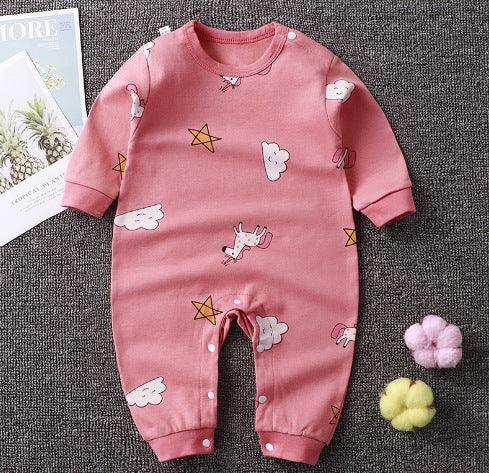 Pink baby romper with unicorn, star, and cloud prints on gray background with decorative pom-poms