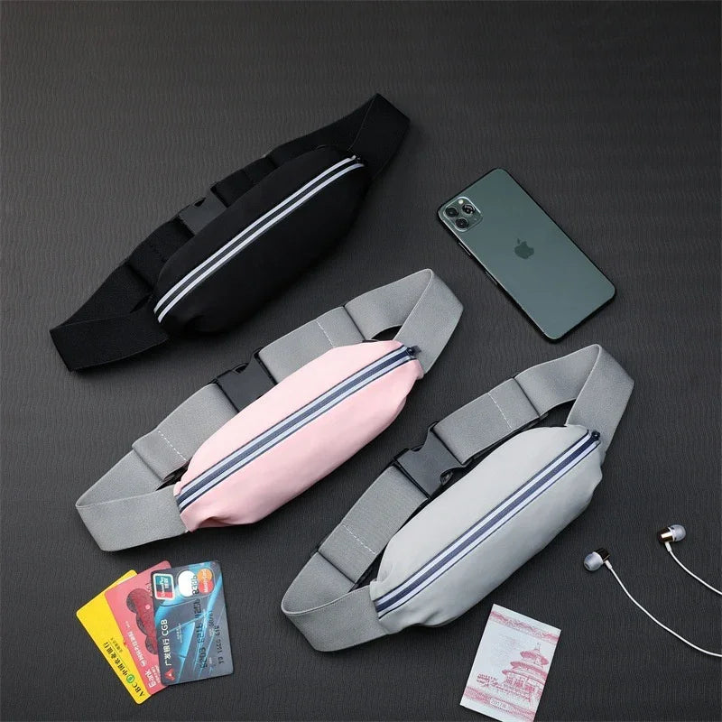 Three waist bags in black, pink, and gray with phone, cards, passport, and earphones on a dark surface
