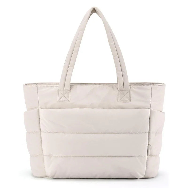 Beige padded tote bag with dual handles and front pocket, minimalist quilted design