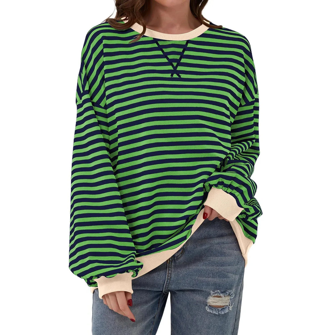 Woman wearing green and navy striped oversized sweatshirt with beige cuffs and ripped jeans