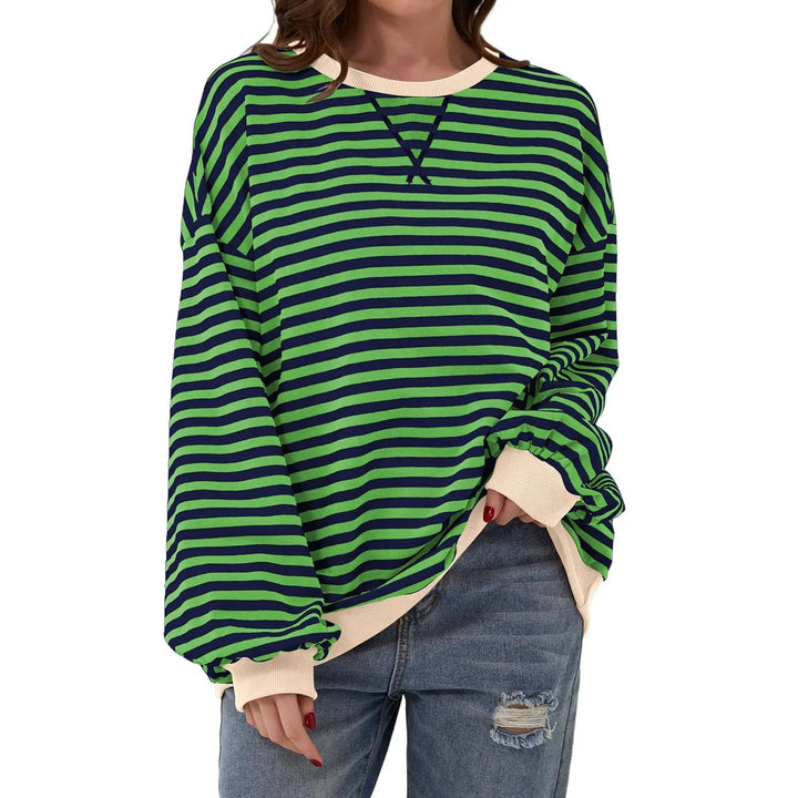 Woman wearing green and navy striped oversized sweatshirt with beige cuffs and ripped jeans