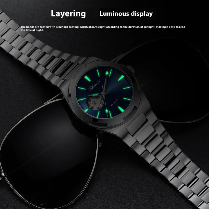 Luminous watch with glowing green hands and markers on metal band displayed with black sunglasses